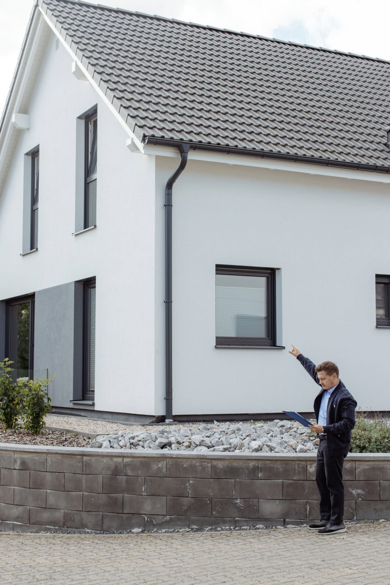 Modernes Reihenhaus mit weißen Fassaden und dunklen Fenstern, Immobilienbewertung durch einen Experten.